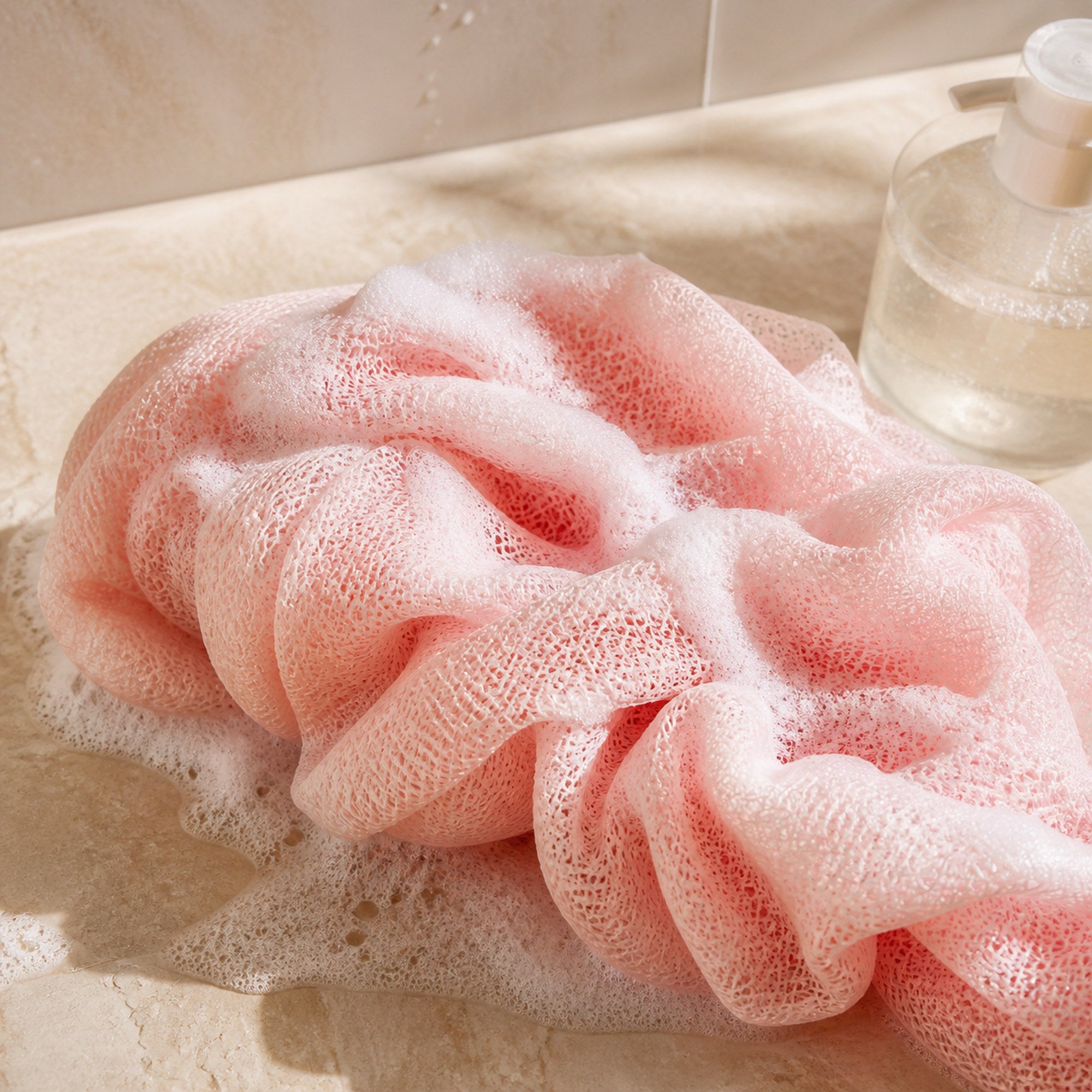 Blush pink African net sponge with rich foam on a clean bathroom surface